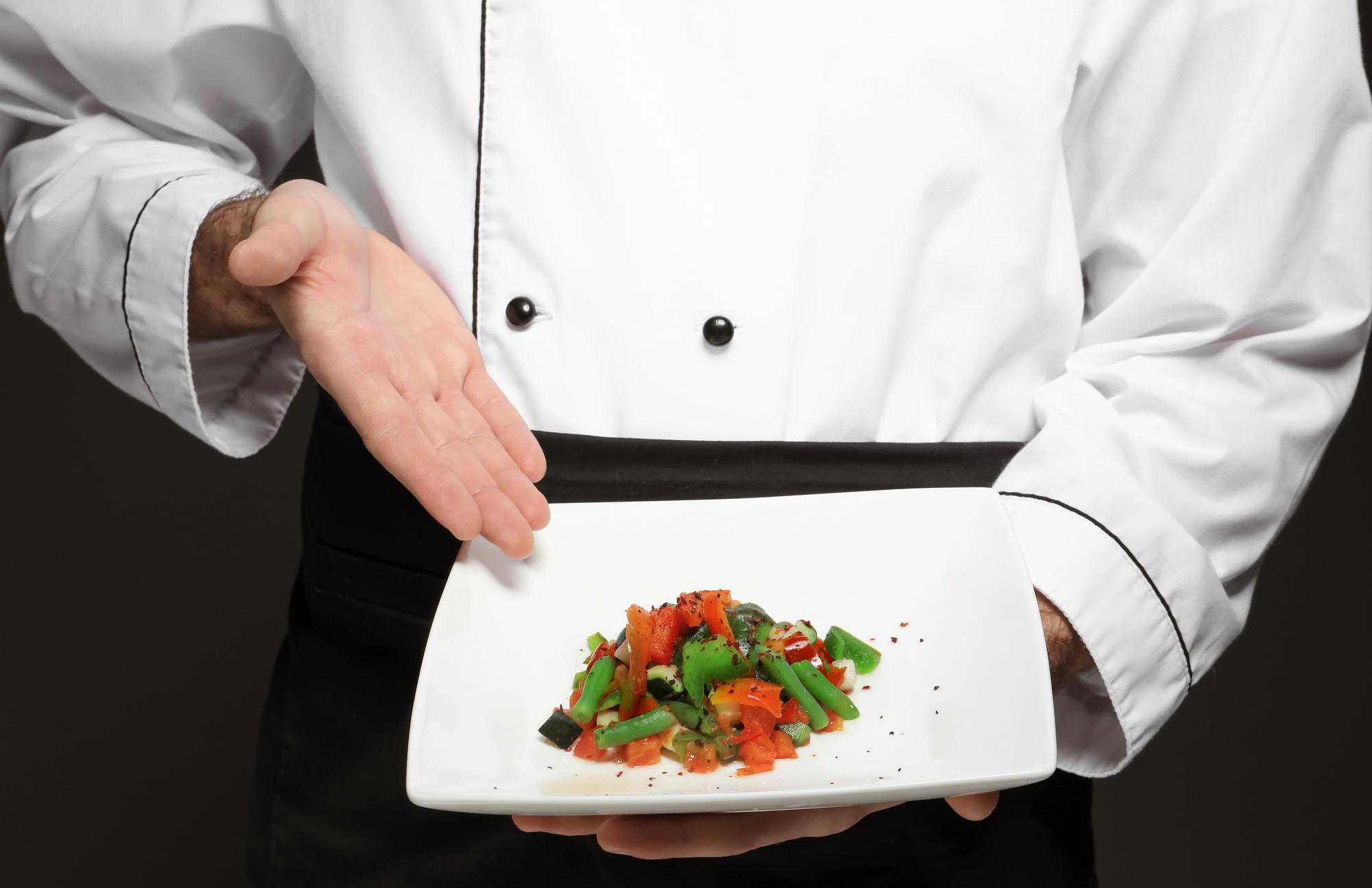 Chef che prepara una composizione gourmet su tavolo elegante